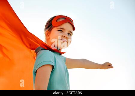 Ritratto di Superhero capretto contro sfondo blu del cielo. Concetto di gioia e infanzia Foto Stock