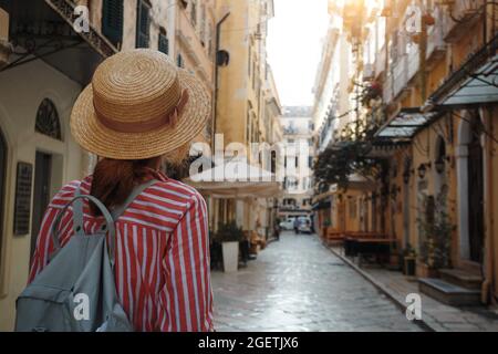 Ragazza in un cappello cammina sulla strada dell'antica città greca. Isola di Corfù in Grecia, Foto Stock