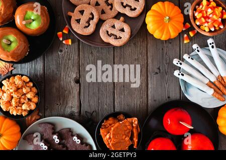 Cornice rustica Halloween trattamento su uno sfondo di legno scuro con spazio copia. Vista dall'alto. Selezione di mele candite, biscotti, caramelle e dolci. Foto Stock