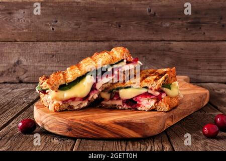 sandwich alla griglia con tacchino, mirtilli e brie. Vista laterale su un piano di servizio su sfondo di legno scuro. Foto Stock