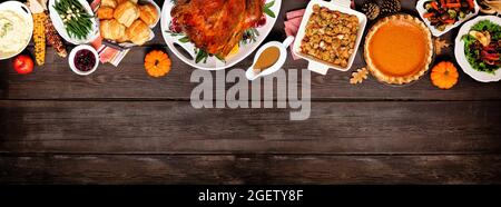 Tradizionale cena di tacchino del Ringraziamento. Sopra il bordo superiore della vista su uno sfondo di banner di legno scuro con spazio di copia. Tacchino, purè di patate, condimento, pum Foto Stock