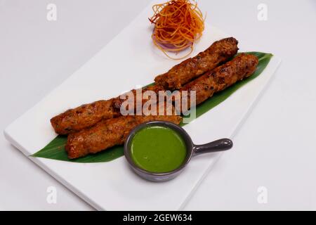 kebab di agnello seekh (spiedino di carne di montone tritata) servito con chutney di menta, cibo indiano di strada Foto Stock