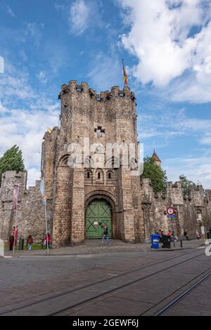 Gent, Fiandre, Belgio - 30 luglio 2021: Ingresso in pietra marrone e porta di Gravensteen, lo storico castello in pietra sotto il paesaggio blu nuvoloso. Qualche volpe verde Foto Stock