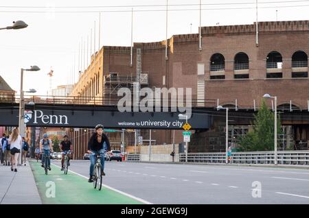 I ciclisti che percorrono le strade della città, piste ciclabili con auto e traffico, University City, Philadelphia, Pennsylvania, USA Foto Stock