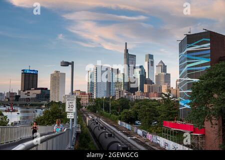 People of Pedestrian Bridge con Skyline con Schuylkill River Boardwalk al tramonto, Philadelphia, Pennsylvania, USA Foto Stock