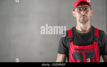 Ritratto di professionista industriale caucasico nel suo 40s indossando occhiali di sicurezza e uniforme rossa. Spazio copia lato sinistro. Foto Stock