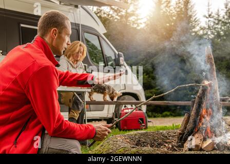 Tema dei veicoli da diporto moderni. Weekend RV Camping Getaway. Amici caucasici di fronte a un Campfire. Road Trip e il Van Life. Foto Stock