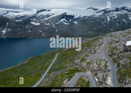 Auto con turisti sulla strada panoramica alpina vicino al famoso Geiranger, Vestland County, Norvegia. Vista aerea. Foto Stock