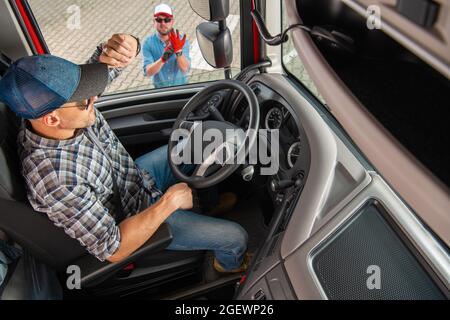 Il moderno conducente di veicoli semi-camion parla con il dispatcher del veicolo, assicurandosi che la consegna venga effettuata in tempo. Foto Stock