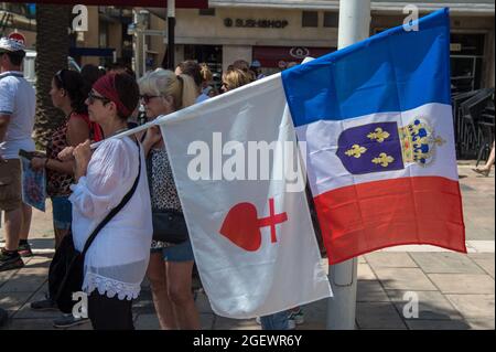 Toulon, Francia. 21 Agosto 2020. Una donna che detiene bandiere riferite ai reali e al cuore cattolico della Vandea, durante la protesta.Sabato 21 agosto 2021 è il sesto giorno di mobilitazione contro la politica del vaccino e l'applicazione del pass sanitario. A Tolone (Var), secondo le autorità, vi erano 6000 manifestanti. I principali slogan criticano le decisioni del governo come dittatoriali. Alcuni cartelli includevano segni e slogan che confrontavano la situazione attuale con il regime nazista e la seconda guerra mondiale. Credit: SOPA Images Limited/Alamy Live News Foto Stock