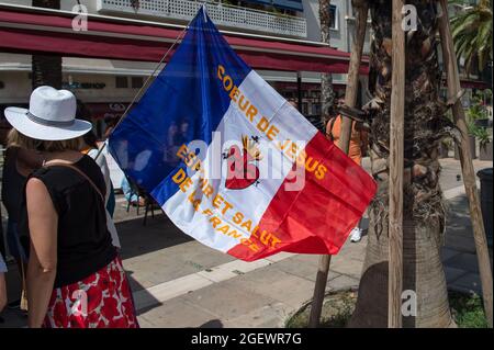 Toulon, Francia. 21 Agosto 2020. Durante la protesta si vede una donna che porta una bandiera di estremisti cattolici, che sono uno degli organizzatori. Sabato 21 agosto 2021 è il sesto giorno di mobilitazione contro la politica vaccinale e l'applicazione del pass sanitario. A Tolone (Var), secondo le autorità, vi erano 6000 manifestanti. I principali slogan criticano le decisioni del governo come dittatoriali. Alcuni cartelli includevano segni e slogan che confrontavano la situazione attuale con il regime nazista e la seconda guerra mondiale. Credit: SOPA Images Limited/Alamy Live News Foto Stock