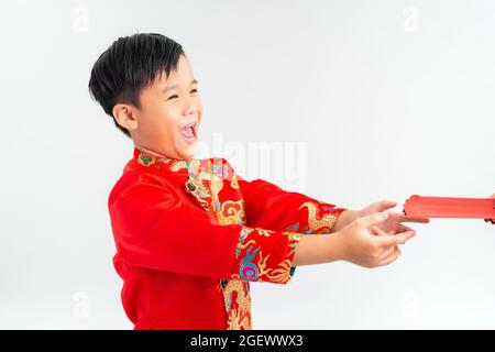 Piccolo ragazzo vietnamita che tiene le buste rosse per Tet. E 'il dono in lunare nuovo anno o Tet Holiday su fondo isolato Foto Stock