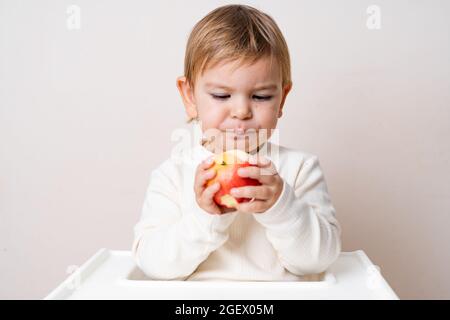 Bambino più piccolo con le mele sulla sedia alta. Mangiare sano. Raccolta estiva e autunnale. Scatto in studio Foto Stock