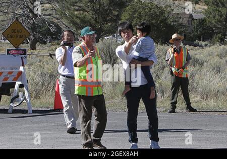 Un volontario alce Rut con giubbotto di sicurezza in colloqui con un uomo che tiene un bambino giovane mentre sono entrambi puntando dietro il volontario del ranger del rutore della macchina fotografica.Elk che tiene i visitatori ad una distanza sicura dall'alce in Mammoth Hot Springs; Data: 25 settembre 2014 Foto Stock