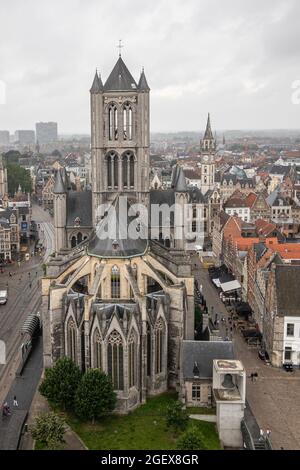 Gent, Fiandre, Belgio - 30 luglio 2021: Edificio storico medievale della chiesa di Sint Niklaas sotto il cielo grigio piovoso con la torre dell'orologio postale nel retro come parte o Foto Stock