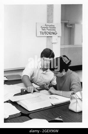 Austin Texas USA, circa 1993: Tutor ispanico maschile al college della comunità aiuta la studentessa femminile con il suo coursework contabile. ©Bob Daemmrich Foto Stock