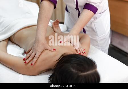 Massaggiatore professionista che fa massaggio del corpo per la giovane  donna sdraiata sopra tavolo massaggiante Foto stock - Alamy