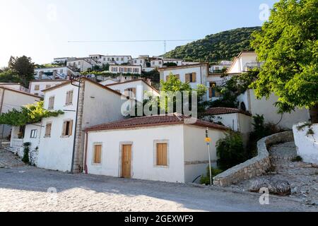 Vista del villaggio Vuno - tradizionali case bianche con tetti arancioni e persiane di legno sulle finestre, sulla collina di montagna, Albania del Sud Foto Stock