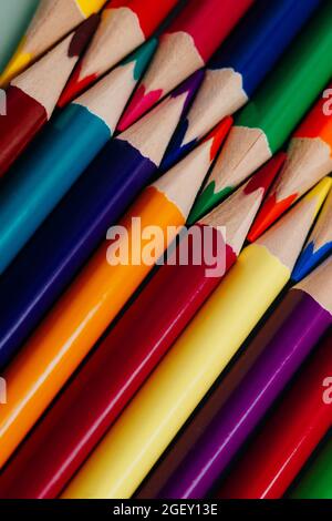 Matite colorate affilate giacciono in un primo piano di fila. Solido sfondo astratto di matite di legno multicolore. Si tratta di forniture scolastiche. Foto Stock