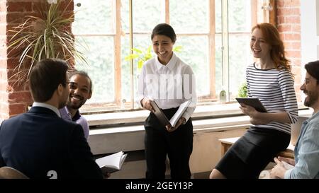 Il leader indiano e il personale diversificato ridono durante una riunione in ufficio Foto Stock