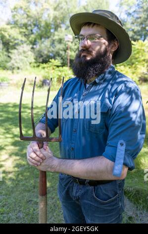 Un bel rancher caucasico che tiene una forchetta nel campo Foto Stock