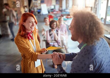 giovane redhead femmina che riceve diploma e congratulazioni dopo il successo del seminario Foto Stock