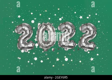 Palloncini in lamina d'argento numero 2022 e confetti su sfondo di gres. Disposizione piatta Foto Stock