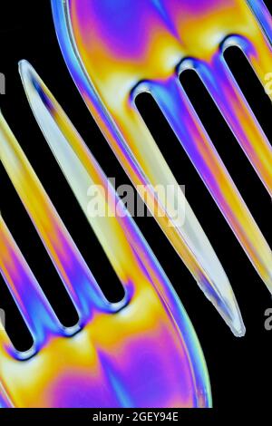 Sulle forcelle in plastica trasparente si formano motivi colorati causati dalla rifrazione della luce polarizzata Foto Stock