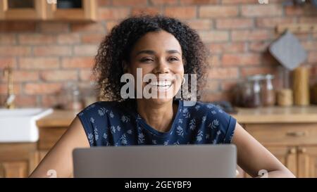 Felice millennial Black donna ridendo a casa al notebook Foto Stock