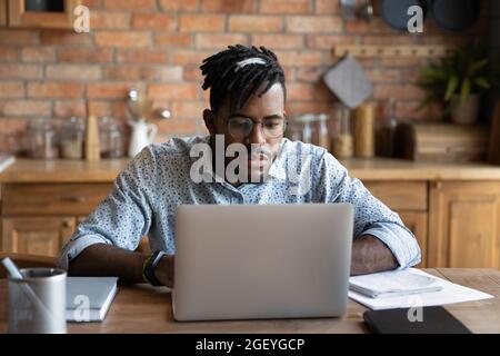 Studente africano concentrato che studia da casa, guardando il webinar di apprendimento Foto Stock