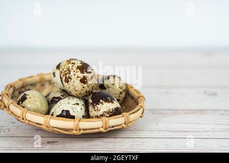 Alcune uova di quaglia in un cestino di rattan. Punti di messa a fuoco selettivi. Foto Stock