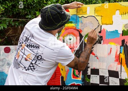 Vista posteriore di un artista maschile che rifiniva il suo dipinto su tela in piedi in un giardino. Foto Stock