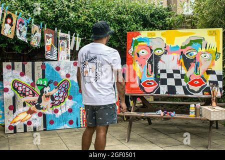 Vista posteriore di un artista maschile che rifiniva il suo dipinto su tela in piedi in un giardino. Foto Stock