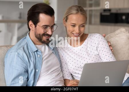 Felice giovane coppia sposata con un computer portatile godendo il tempo libero a casa Foto Stock