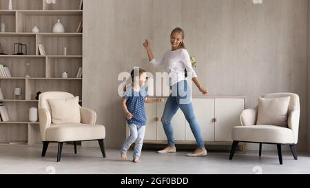 Buona bambina e mamma che ballano alla musica a casa Foto Stock