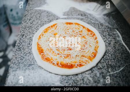 Una pizza Margherita in attesa di un bancone da mettere in forno Foto Stock