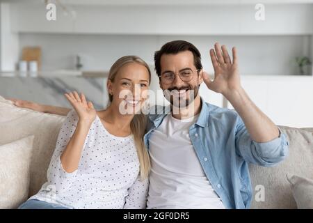 Felice coppia millenaria che salutano, sorridendo alla webcam Foto Stock