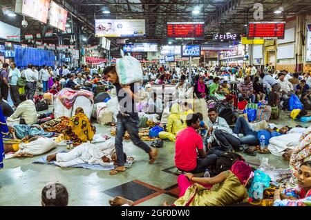 Mumbai, Maharashtra, India : i viaggiatori aspettano i loro treni all'interno della stazione ferroviaria Chhatrapati Shivaji Terminus (ex Victoria Terminus) Foto Stock