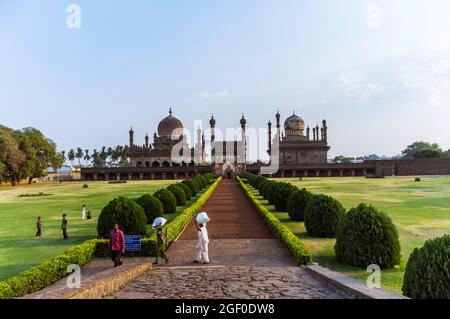 Bijapur, Karnataka, India : i lavoratori camminano oltre il 17 ° secolo Ibrahim Rouza mausoleo e moschea considerata come una delle proporzioni più belle Foto Stock