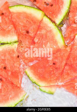 Vista ravvicinata delle fette di melone rosso sullo sfondo della limonata. Texture di rinfrescante dolce d'estate con macroflicine sulla parete di vetro. Piatto Foto Stock