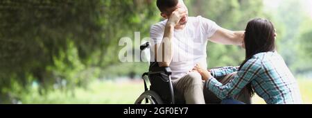 L'uomo disabile in sedia a rotelle comunica con la donna nel parco Foto Stock