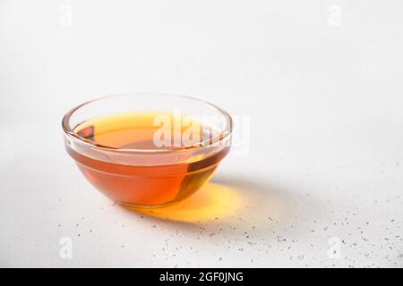 Sciroppo di carciofo di Gerusalemme in recipiente di vetro su sfondo bianco. Primo piano. Sostituto dello zucchero per dolci vegani crudi. Foto Stock