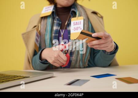 Mani di shopaholic femminile che tagliano le sue carte di credito dopo l'acquisto di troppi vestiti in vendita Foto Stock