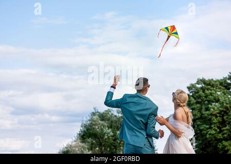 Un aquilone ad un matrimonio. Una coppia di nozze lancia un aquilone nel cielo. Sposi e sposi volano un aquilone insieme il loro giorno di nozze. Foto Stock