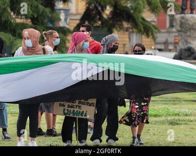 Le ragazze arabe con maschere chirurgiche sui loro volti in piedi l'una accanto all'altra scuotendo una grande bandiera. Foto Stock