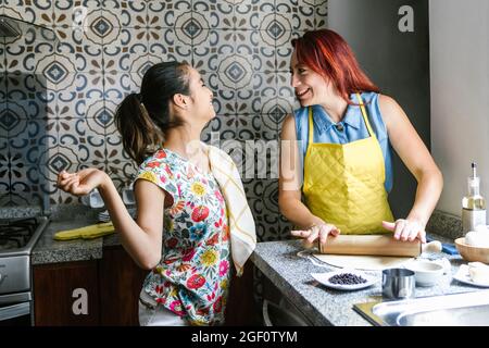 Ragazza ispanica con paralisi cerebrale e sua madre che cucinava a casa, in concetto di disabilità in America Latina Foto Stock