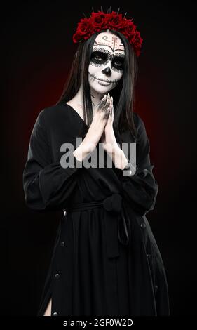 Giovane donna con calavera (cranio dello zucchero) trucco. La ragazza strega con muertos (muerte) greasepaint in abito nero. Tema giorno dei morti (e Halloween) Foto Stock