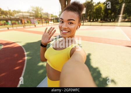 Donna nera che fa selfie foto su smartphone ondeggiante mano Foto Stock