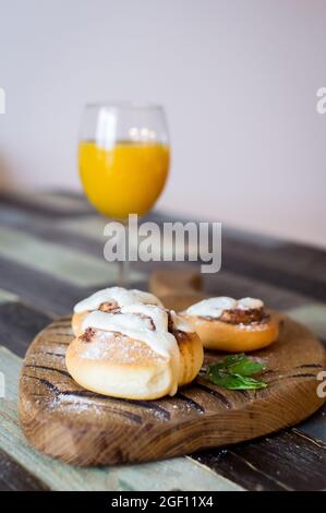 Panini fatti in casa con cannella e un bicchiere di succo di frutta Foto Stock