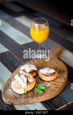 Panini fatti in casa con cannella e un bicchiere di succo di frutta Foto Stock